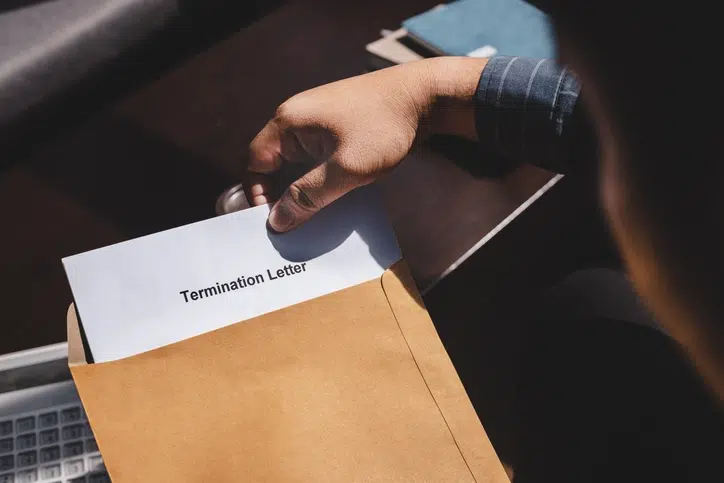 Close-up of a hand placing a termination letter into an envelope, representing wrongful termination in the workplace.