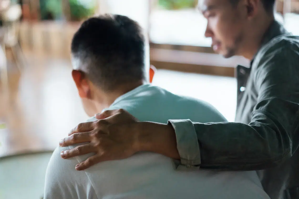 A supportive colleague places a hand on the shoulder of an employee during a private conversation, symbolizing mental disability support at work.