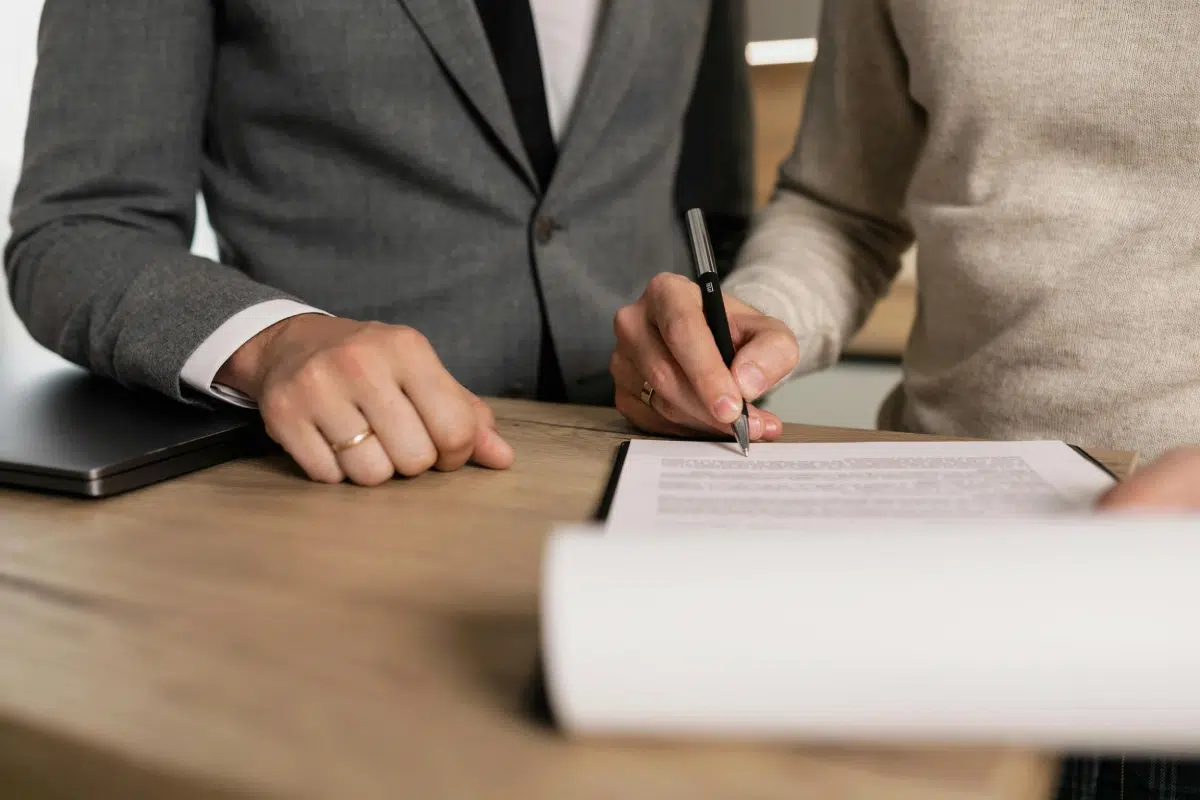 Person in formal attire signing legal documents at a desk, symbolizing action taken for family and medical leave rights enforcement.