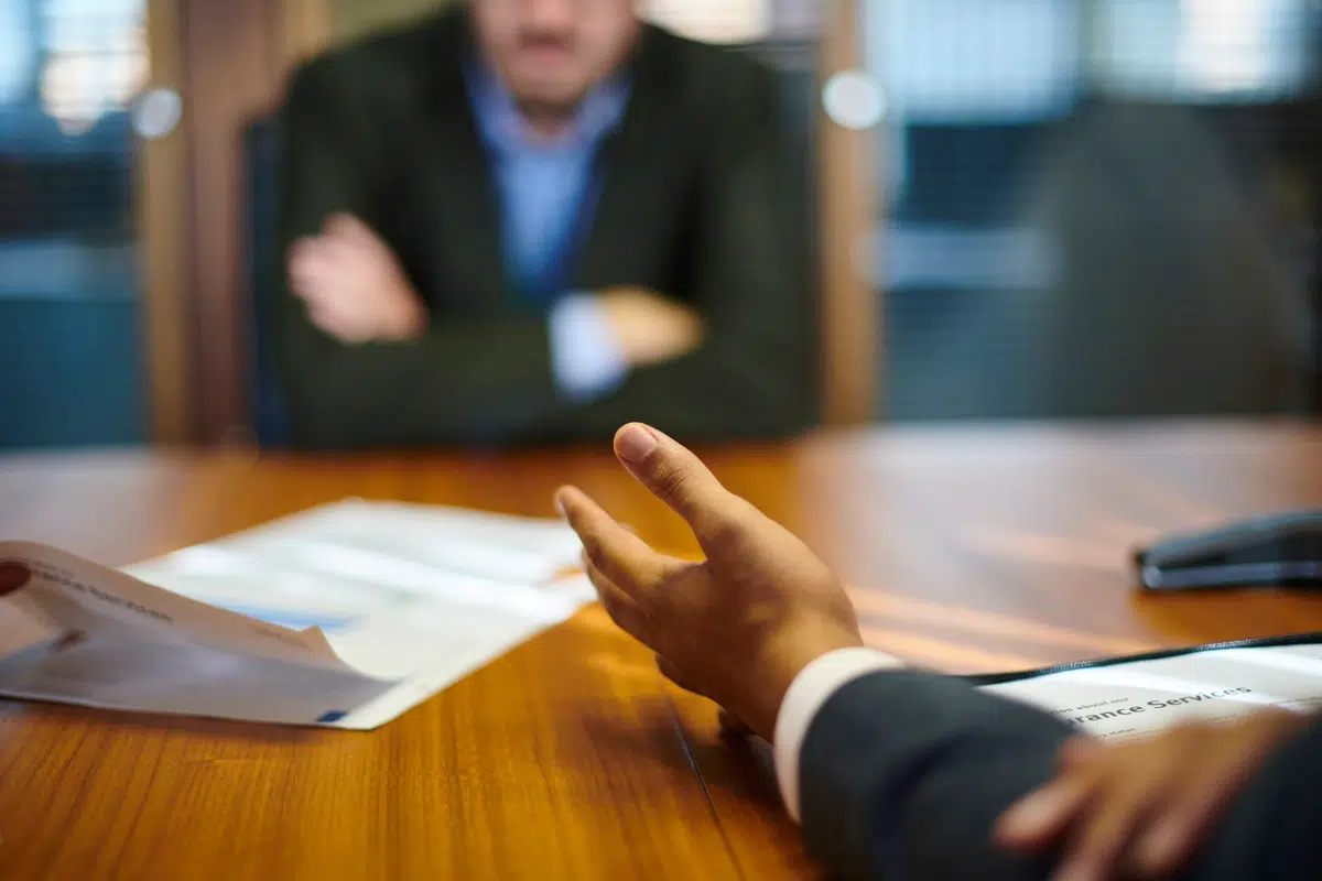 Business professional gesturing during a meeting across the table, symbolizing negotiation over unpaid executive wages.